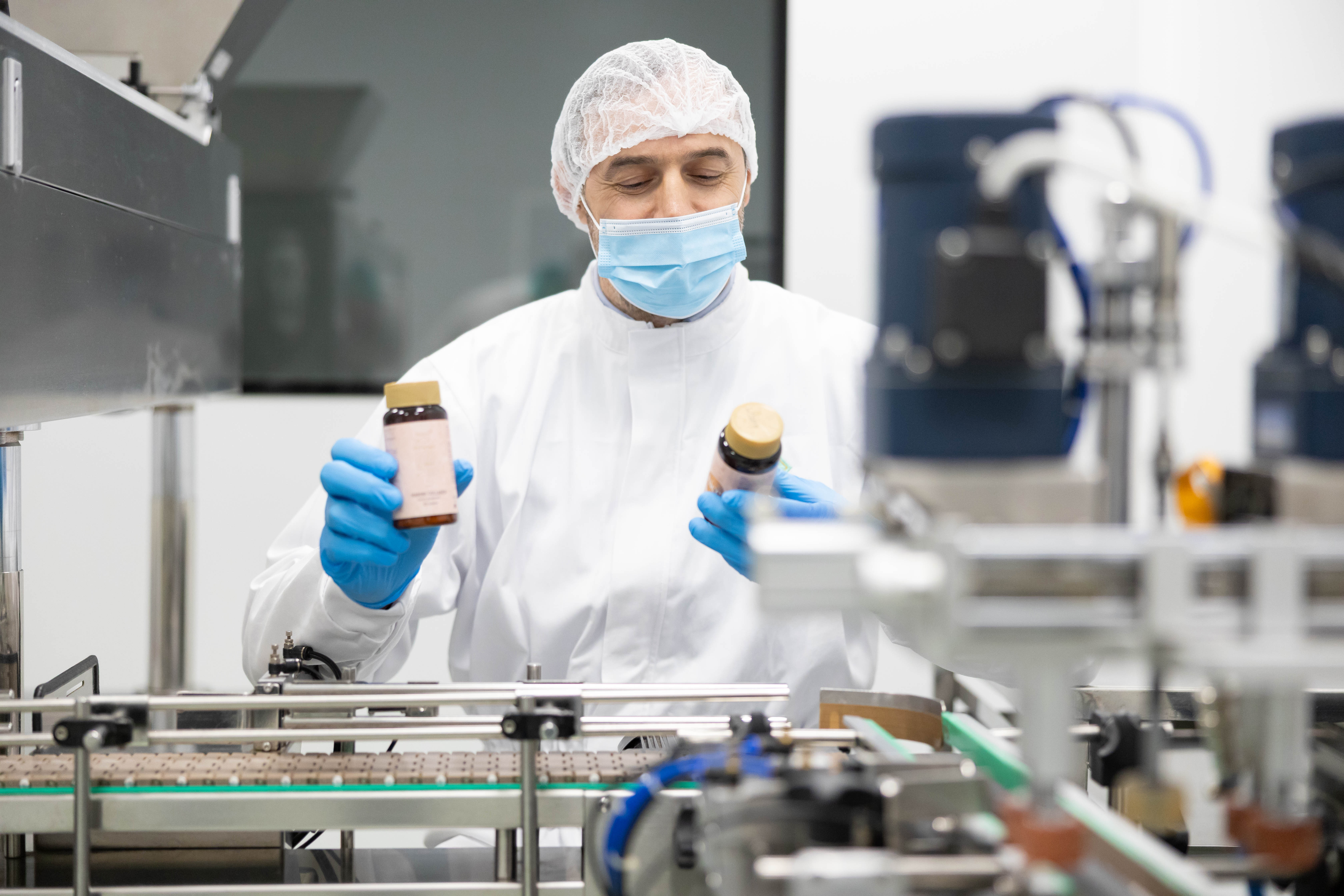 QC technician inspecting finished bottles on a production line